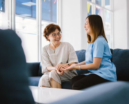 Trained carer using dementia communication training techniques to connect gently with an elderly woman at home